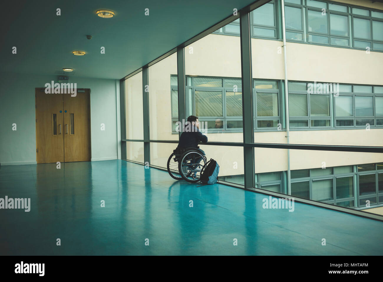 Homme handicapé sur fauteuil roulant à partir de panneau de verre Banque D'Images