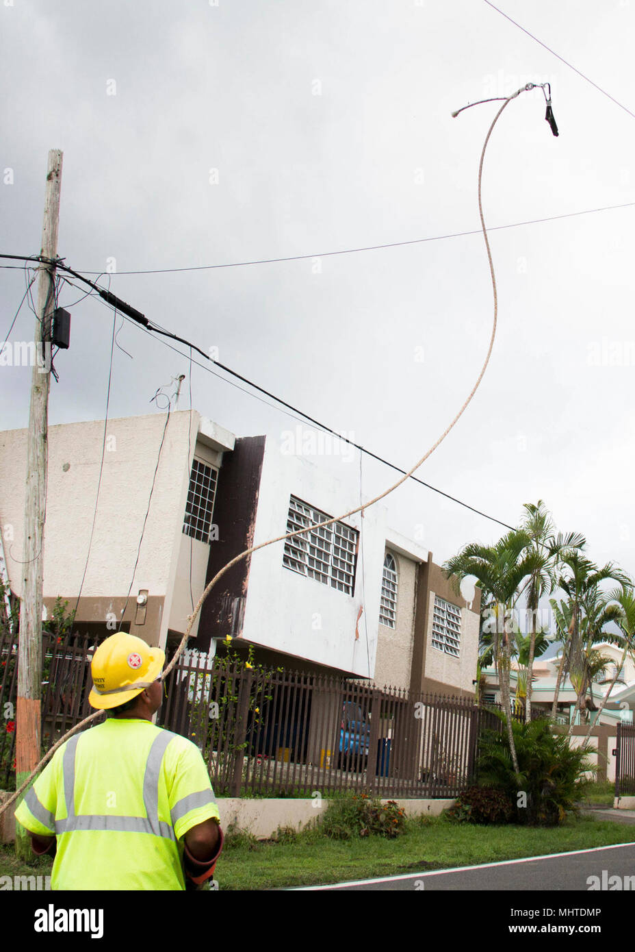Un travailleur de première ligne s'agite un guide corde sur un câble existant. Il va utiliser la corde à tirer une nouvelle ligne en travers de la route.Les équipes de travail dans les lignes électriques réparation d'une montagne à Naranjito. À compter du 26 mars 2018, plus de 94 pour cent des clients de Porto Rico ont le pouvoir restauré. Les six autres pour cent sont situés principalement dans les régions montagneuses. Malgré les difficultés d'accès et de transport, les équipes de travail sur l'île se concentrent leurs efforts dans ces régions éloignées, avec l'objectif d'atteindre 95  % de la restauration de ces régions à la fin de mai. Banque D'Images