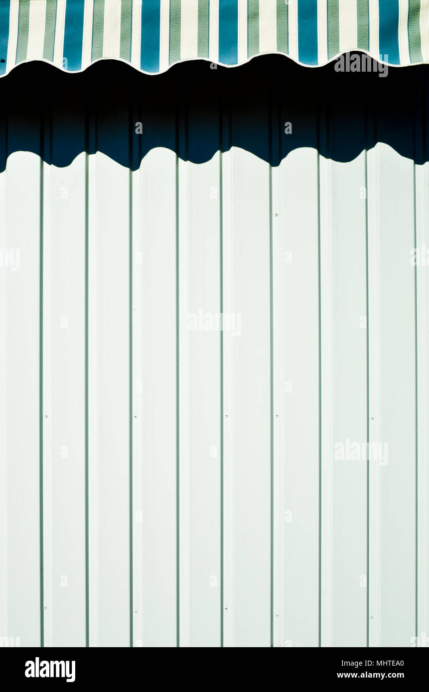 Tente à rayures en projetant une ombre sur un mur blanc Banque D'Images