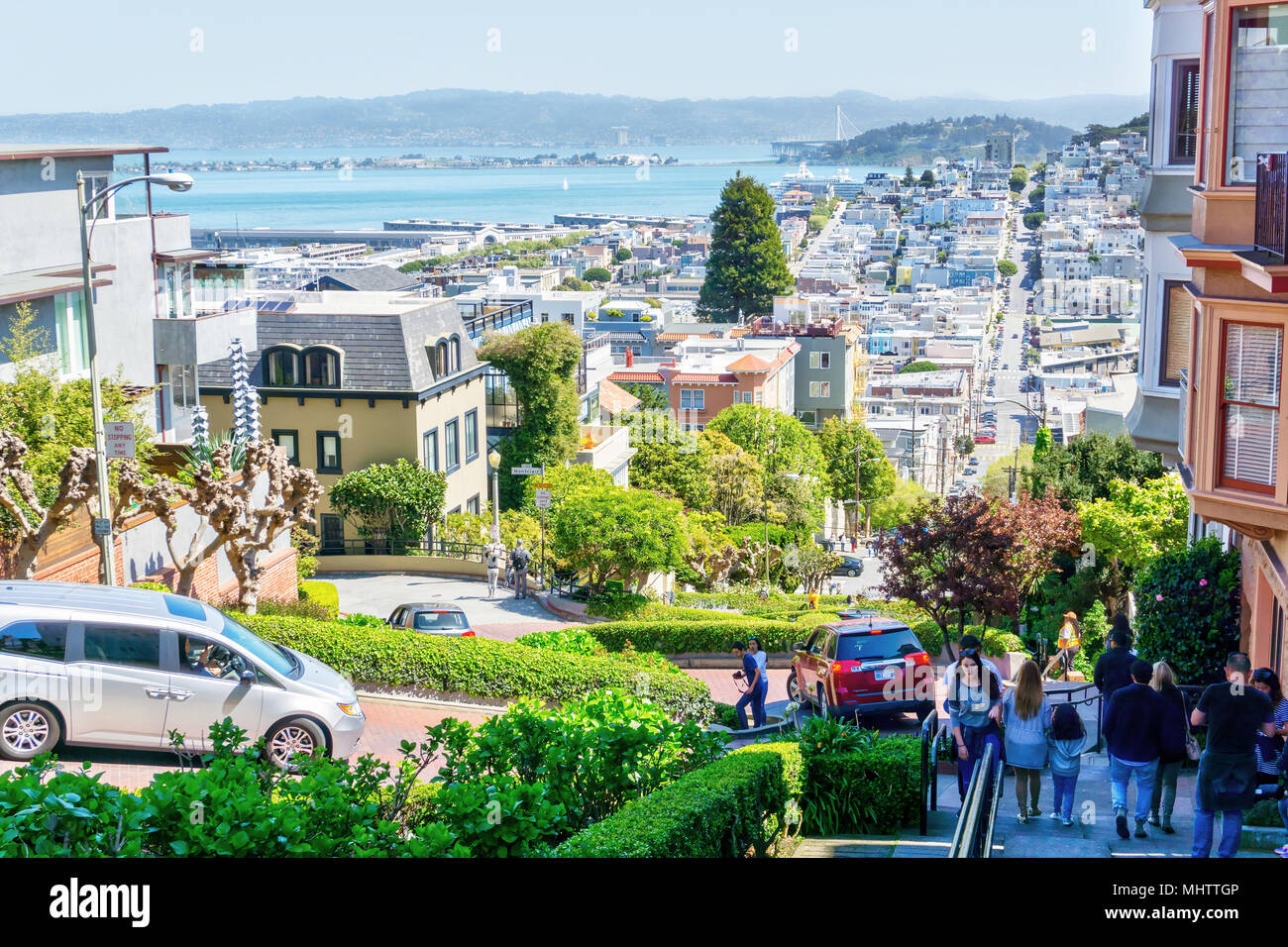 SAN FRANCISCO - Apr 2, 2018 : Voitures descendre Lombard Street avec la ville en arrière-plan montrant la baie de San Francisco. Banque D'Images