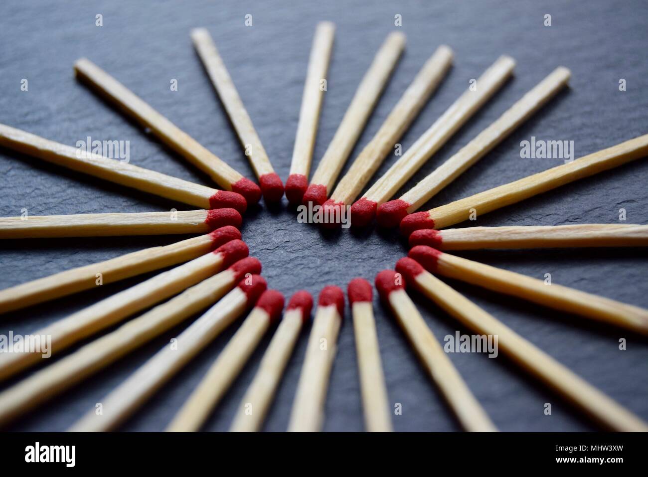 Collection d'allumettes red head, placé dans un coeur sur une forme de formage d'ardoise gris noir arrière-plan. Banque D'Images