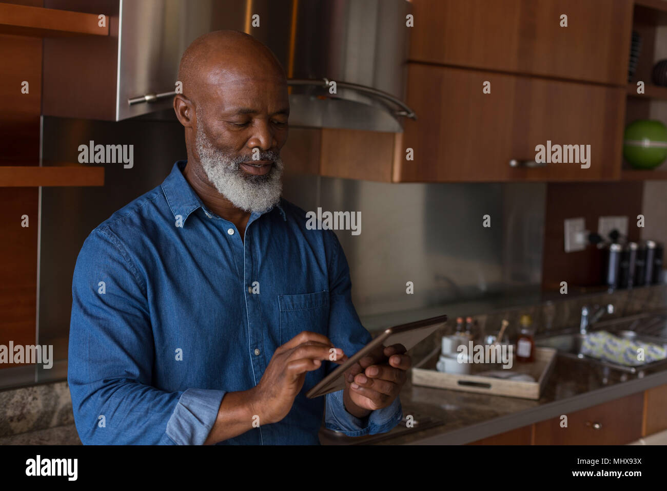 Senior man using digital tablet in kitchen Banque D'Images