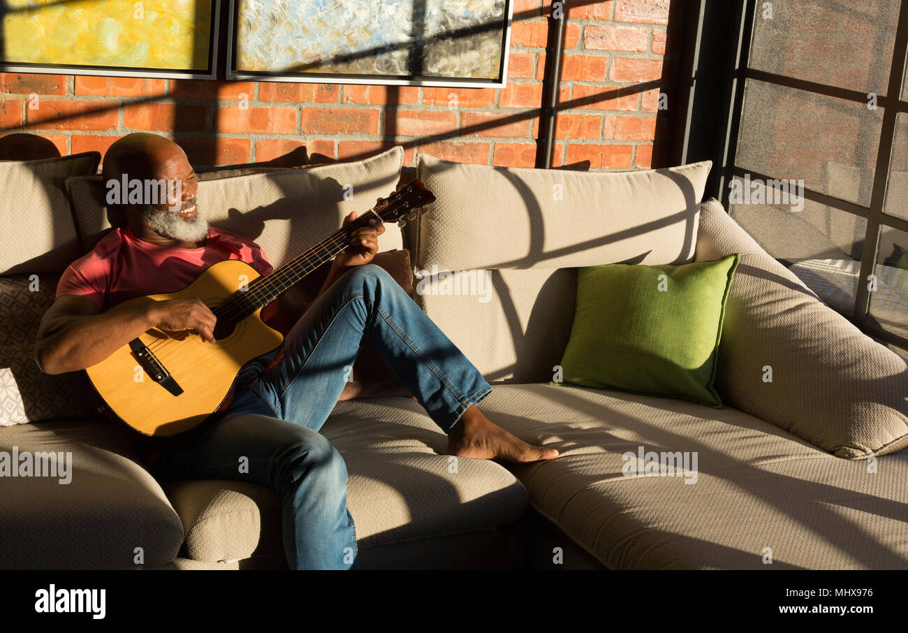 Handsome Guy Dans Un Casque Joue De La Guitare Électrique, En Utilisant Un  Ordinateur Portable Et En Souriant Tout En Étant Assis Sur Le Sol À La  Maison Banque D'Images et Photos