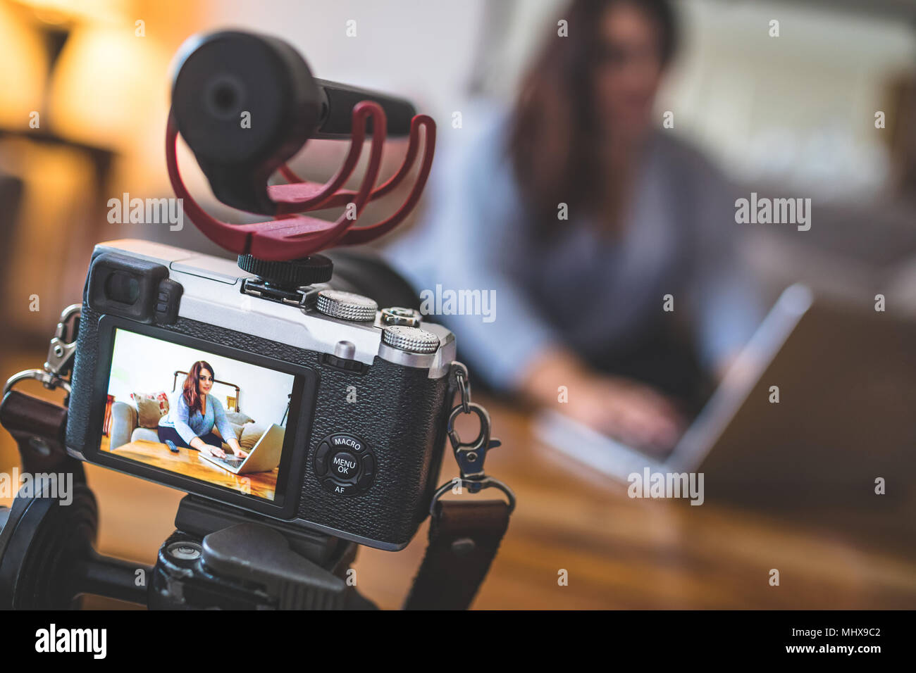 Vlogger femelle sitting on sofa while using laptop Banque D'Images