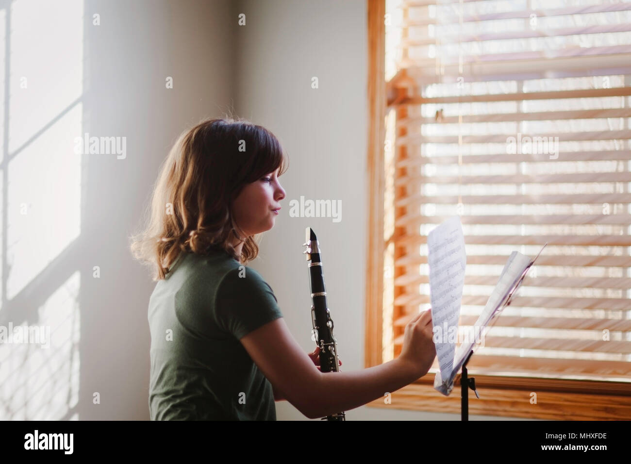 Fille à la pratique de la clarinette par fenêtre Banque D'Images