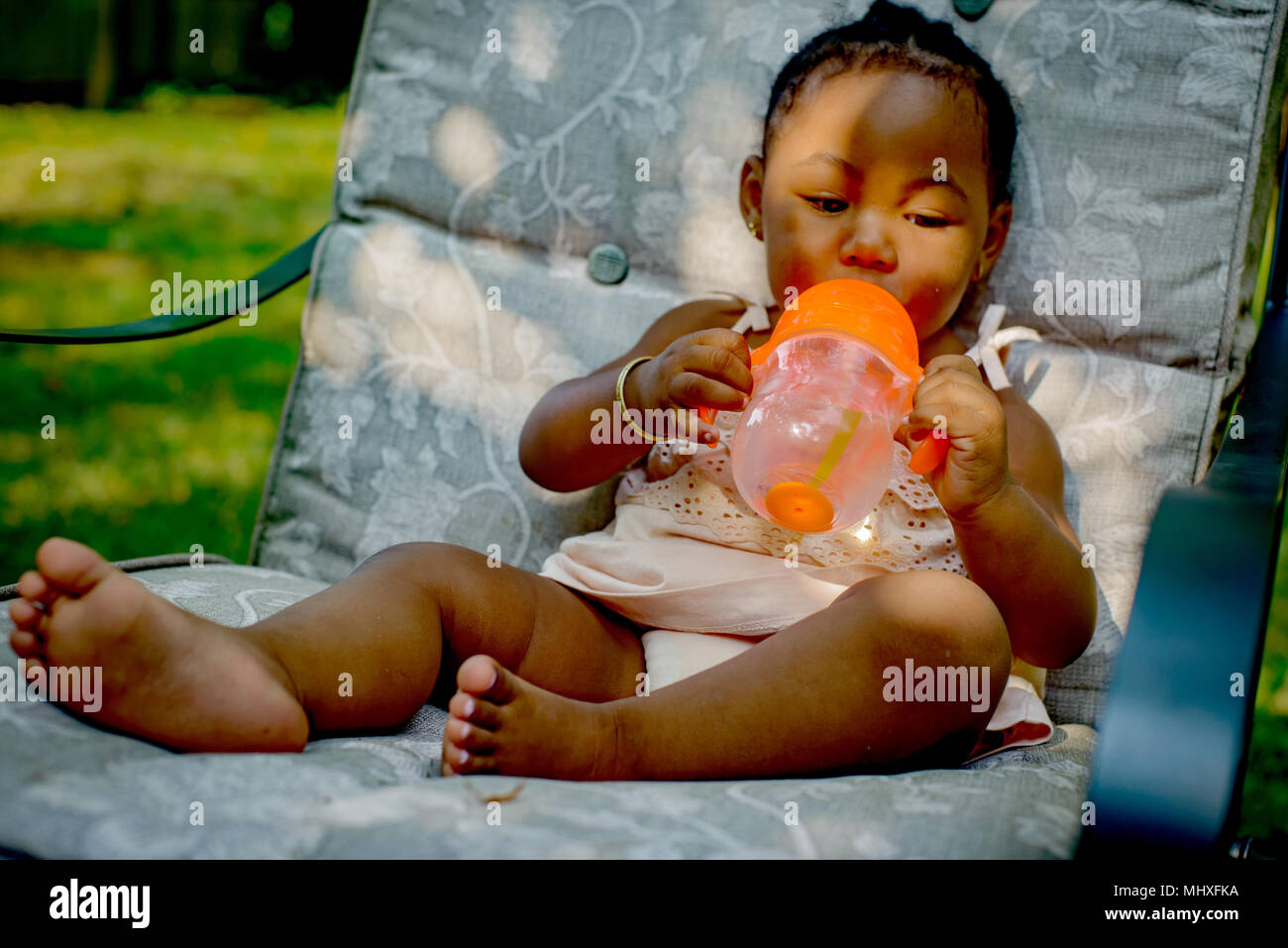 Baby Girl sitting on chaise de salon de jardin coupe de Banque D'Images