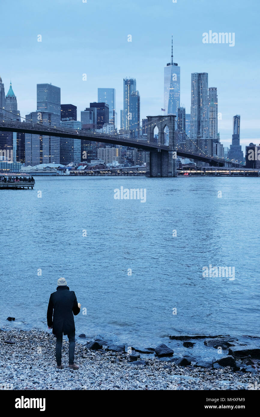 L'homme sur le pont de Brooklyn et Manhattan Skyline à partir de la berge, New York, USA Banque D'Images