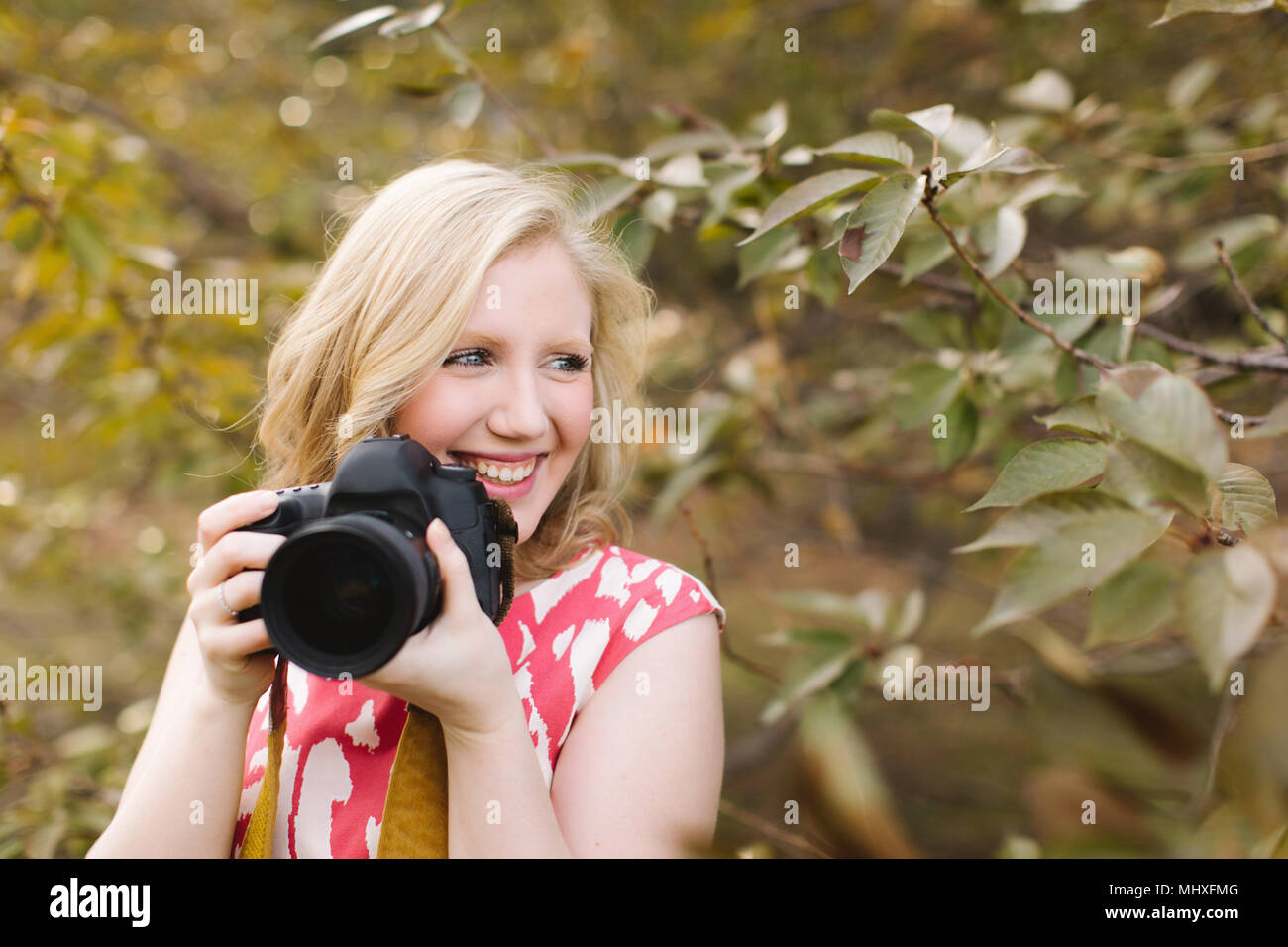 Jeune femme à l'aide de votre appareil photo reflex numérique dans park Banque D'Images