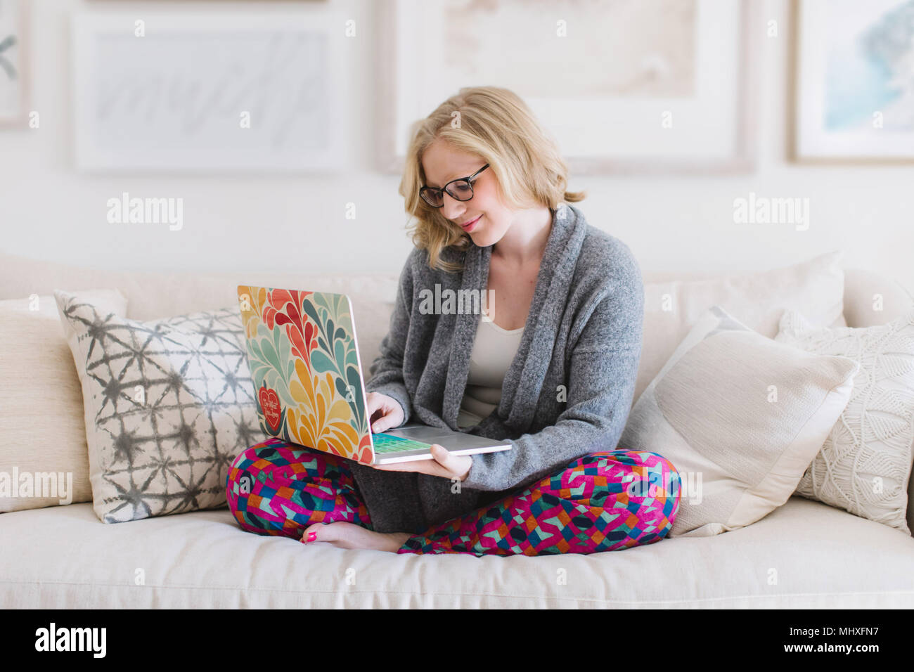 Jeune femme assise sur un canapé-typing on laptop Banque D'Images