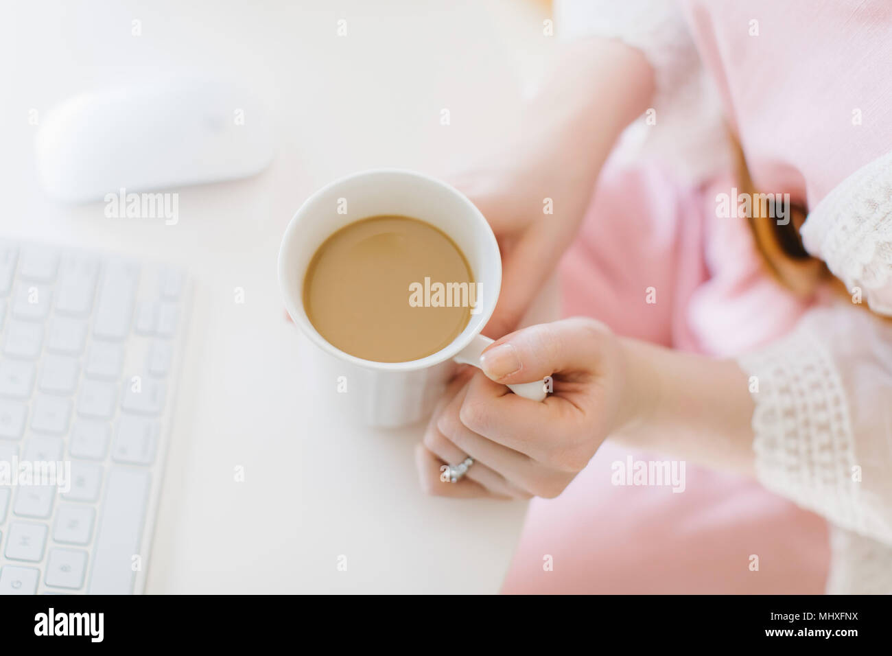 Young woman sitting at computer holding coffee mug, frais généraux vue rapprochée Banque D'Images