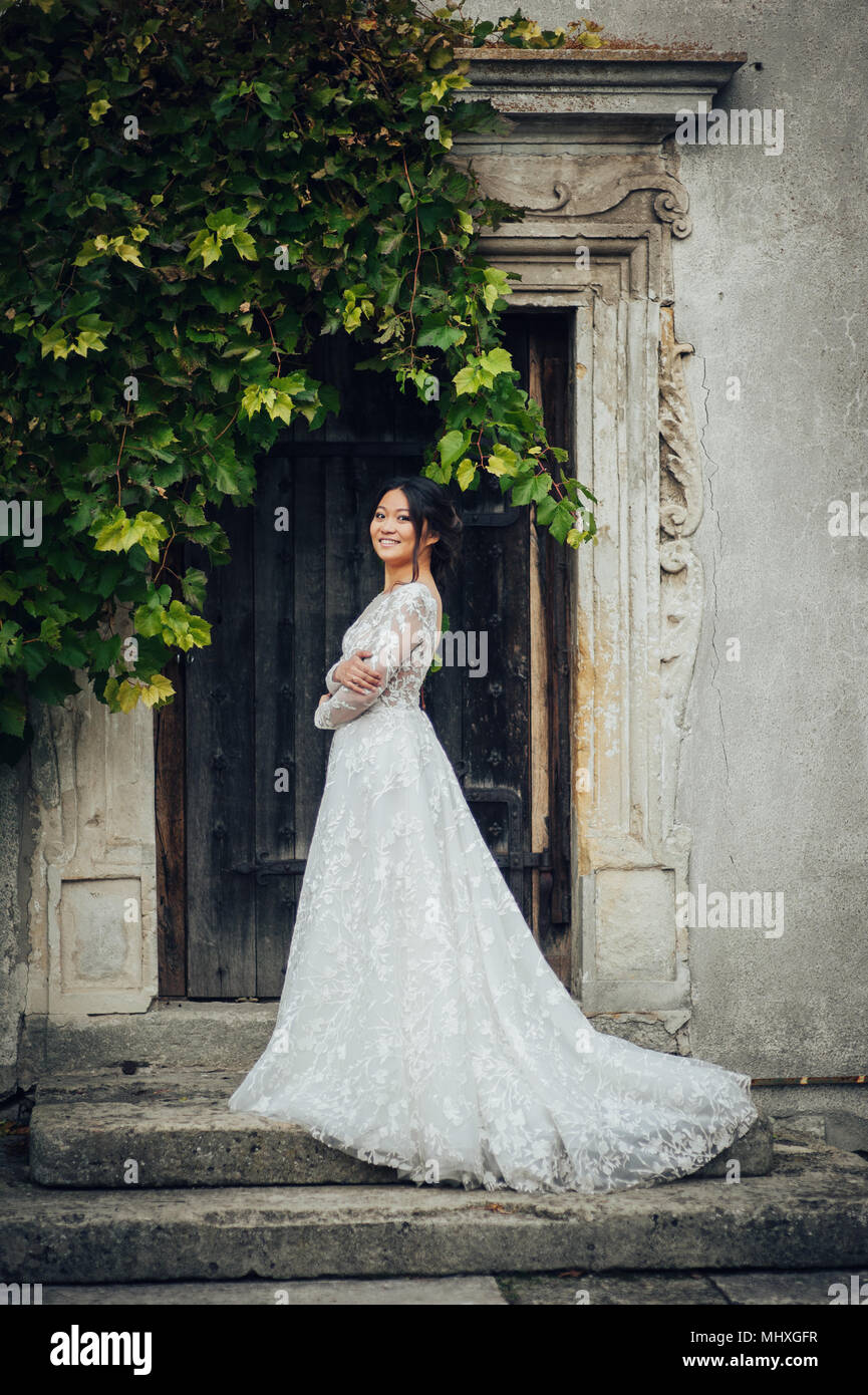 Vue arrière de mariée élégante en robe de mariage contre l'ancienne porte  avec des branches d'arbre vert Photo Stock - Alamy