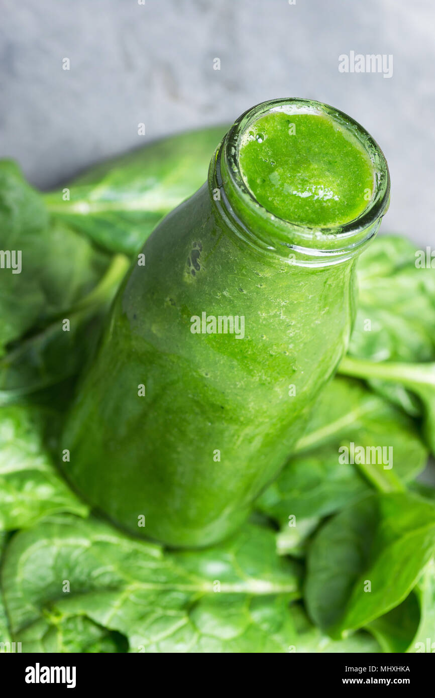 Bouteille avec des matières premières de vert frais Smoothie Légumes verts Légumes Fruits Pommes Bananes Kiwi les courgettes sur les feuilles d'épinards comme arrière-plan. Lifesty sain Banque D'Images