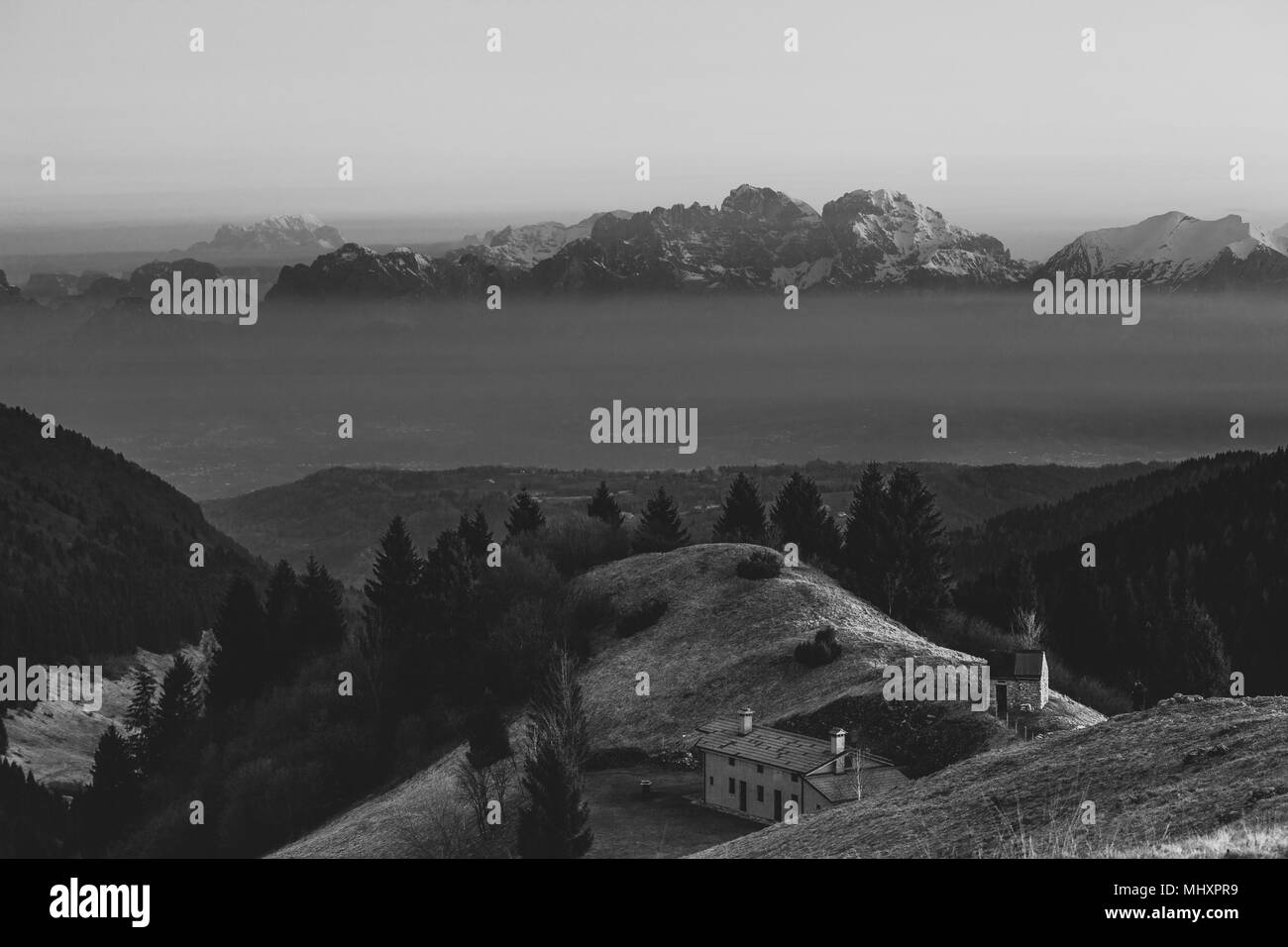 Lever du soleil sur une petite hutte avec en arrière-plan le Mont Schiara dolomite peaks qui émergent de la brume, Pian de le Femene, Veneto, Italie Banque D'Images