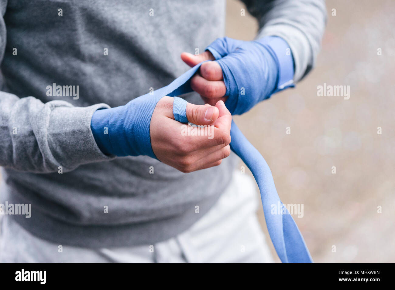 Young male boxer à l'extérieur de la formation, des bandages les mains à côté des enveloppements, mid section Banque D'Images