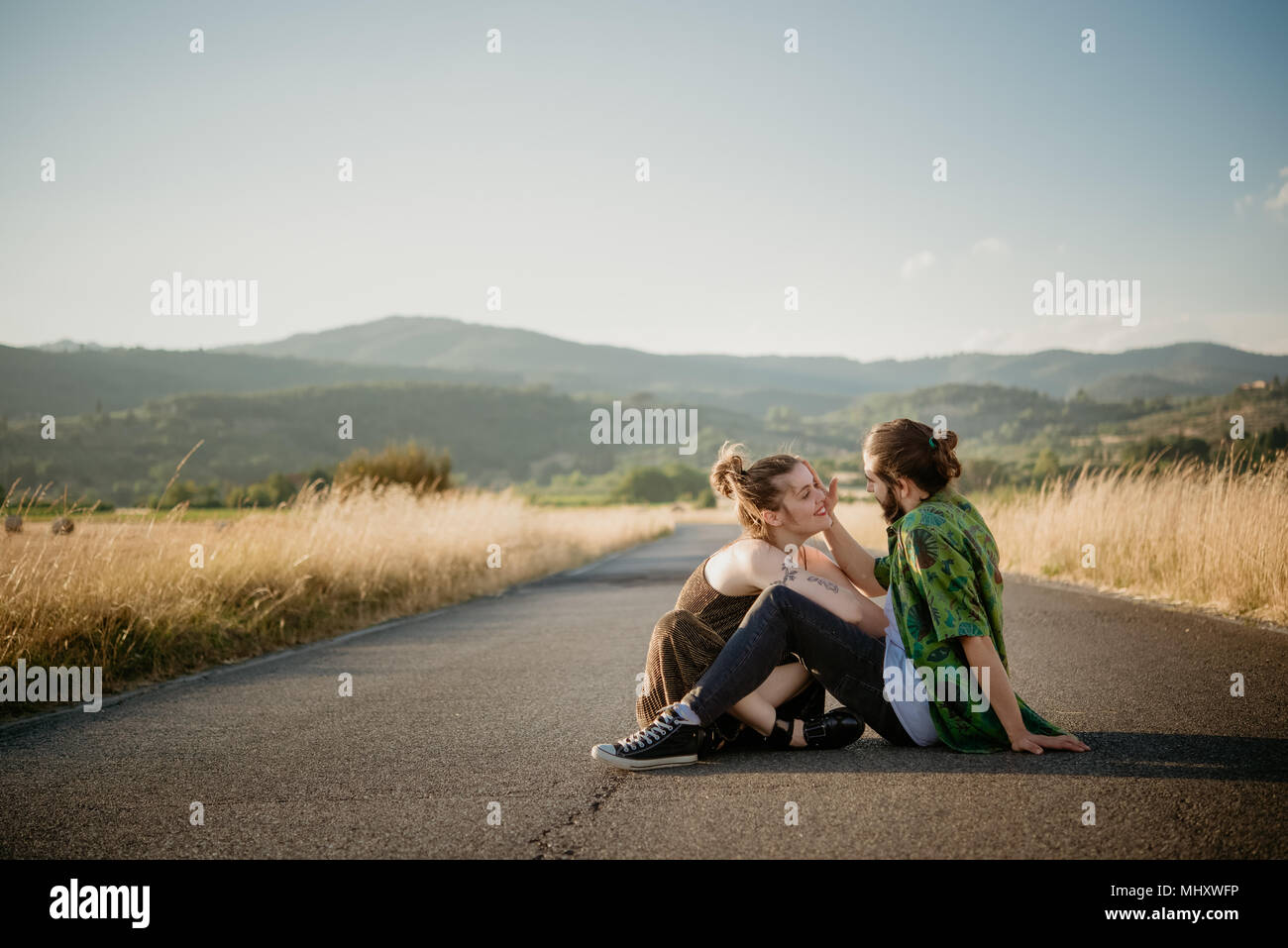 Couple on road par golden grass field, Arezzo, Toscane, Italie Banque D'Images
