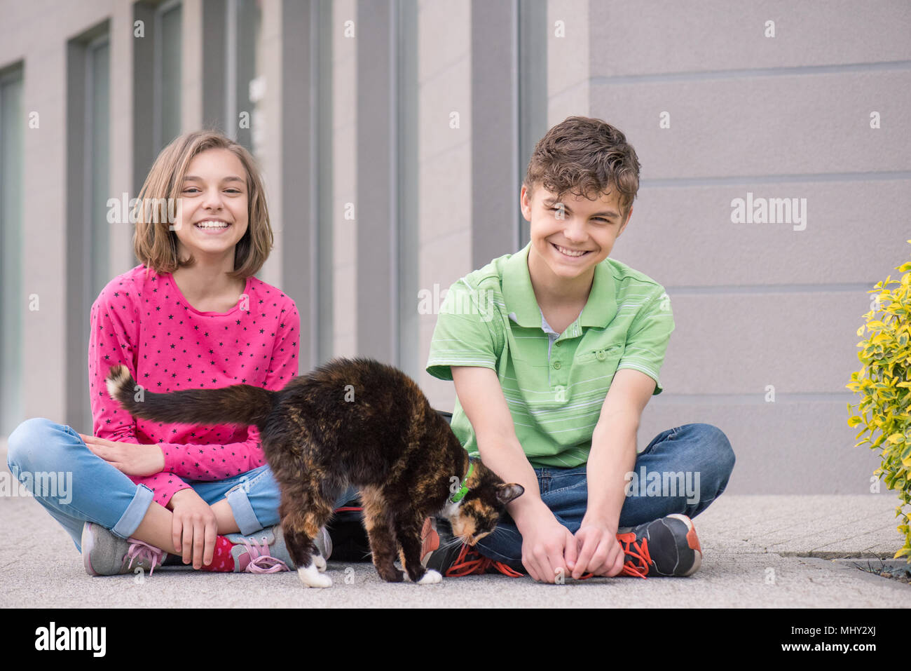 Teen boy and girl Playing with cat Banque D'Images