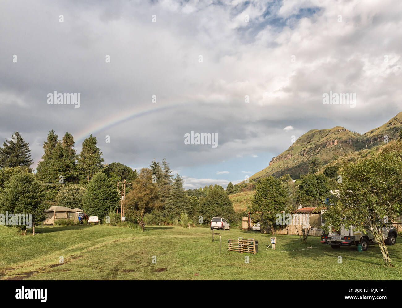 MONKS COWL, AFRIQUE DU SUD - le 18 mars 2018 : un arc-en-ciel sur le camping au bord de moines dans le Drakensberg du Kwazulu-Natal. Une tente et les véhicules sont vis Banque D'Images