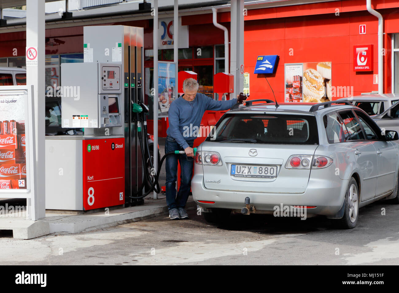 Ornskoldsvik, Suède - le 14 juillet 2015 : une personne d'une voiture de ravitaillement à une station d'essence libre-service service à la marque fpr OKQ8. Banque D'Images