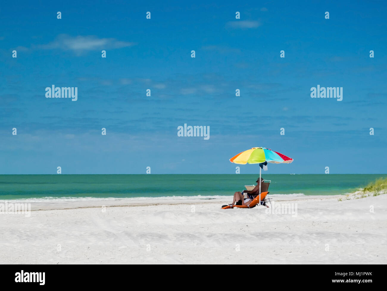 Couple se détendant sous un parapluie sur une plage de Floride. Banque D'Images