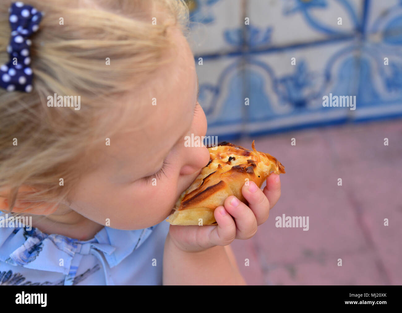 La fille est de manger Pasteis de Belem egg tart. Carrelage azulejos sur un arrière-plan Banque D'Images