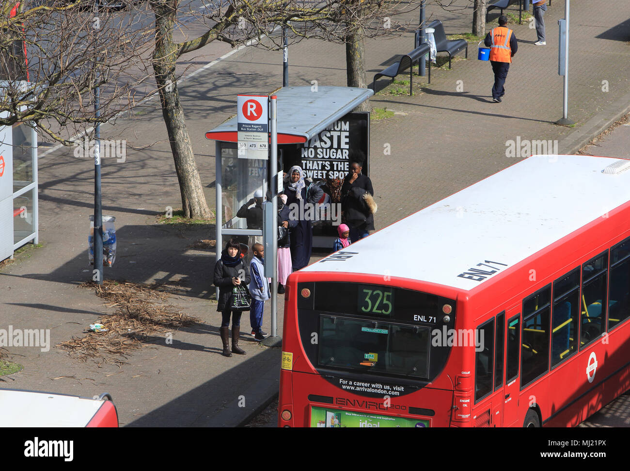 Les gens qui attendent à l'arrêt de bus dans diverses et multiculturelles, Canning Town dans l'Est de Londres, Angleterre, RU Banque D'Images
