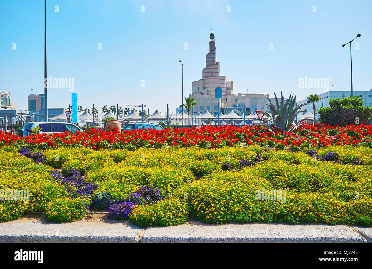 La ville pittoresque de fleurs de Corniche promenade avec Spiral mosquée, aussi célèbre que Al Fanar, sur l'arrière-plan, Doha, Qatar. Banque D'Images