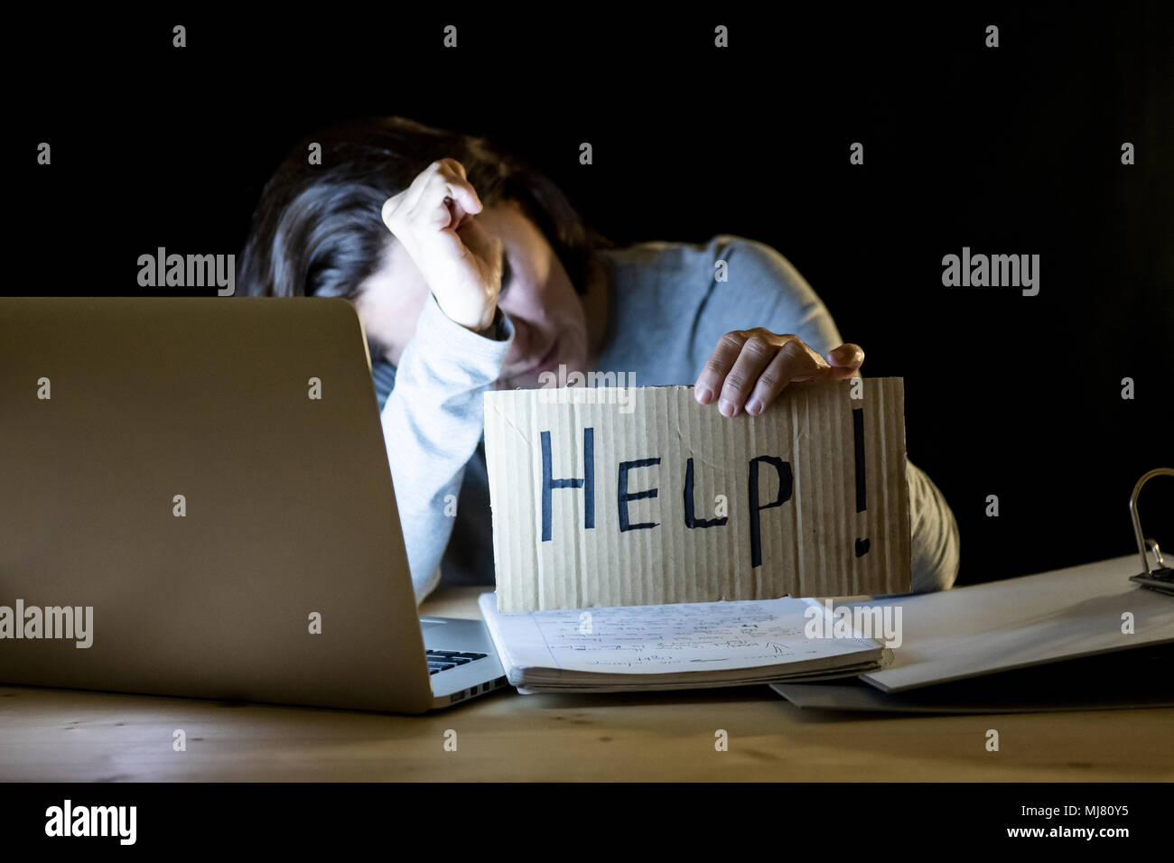 Jeune étudiant fatigué et stressé à la maison travailler tard dans la nuit sur son ordinateur portable avec une aide connexion un plus travaillé et intoxiqué concept sur bla isolés Banque D'Images