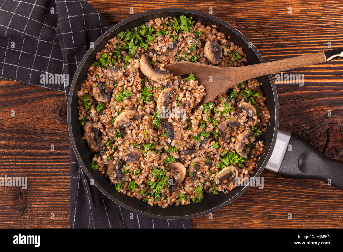 Le sarrasin risotto aux champignons secs dans la casserole du ci-dessus sur table en bois. L'alimentation végétarienne concept. Banque D'Images