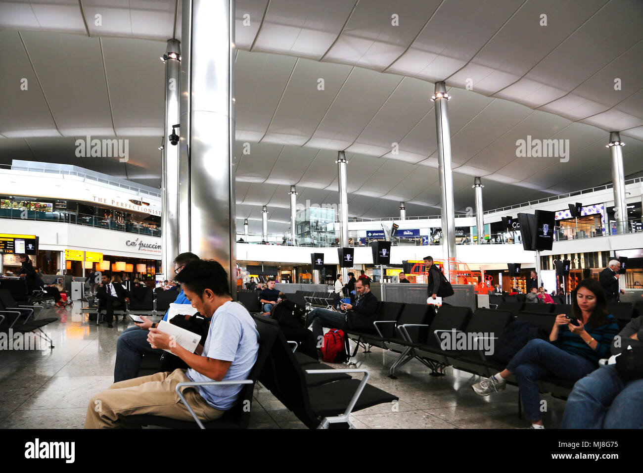 Angleterre Heathrow Airport Terminal 2 passagers en attente pour les vols en salle d'embarquement avec restaurants et boutiques hors taxes Banque D'Images