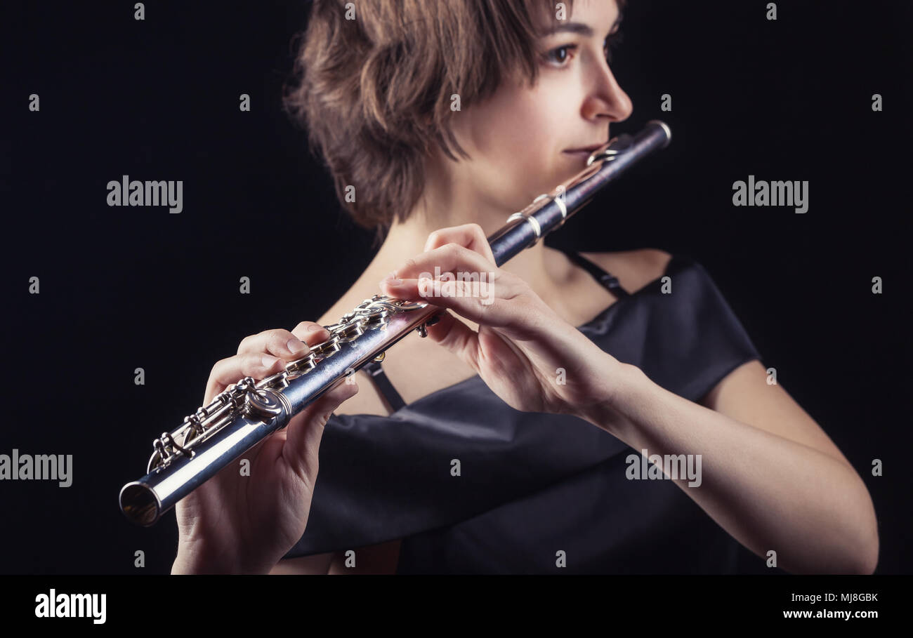 Close-up d'une femme jouant de la flûte sur fond noir Banque D'Images