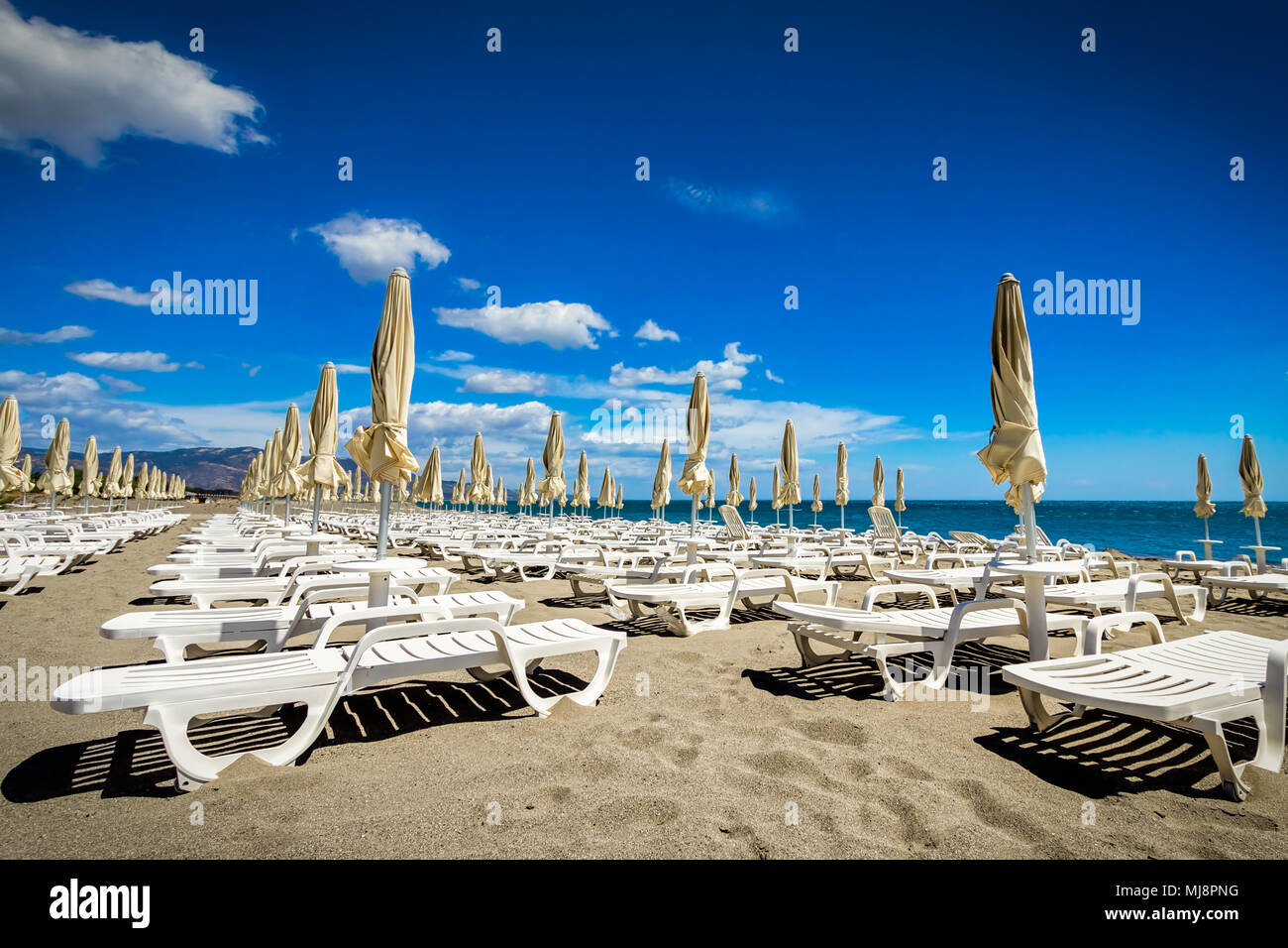 Chaises de plage inoccupé dans le sable sur une journée ensoleillée dans le sud de l'Italie. Banque D'Images