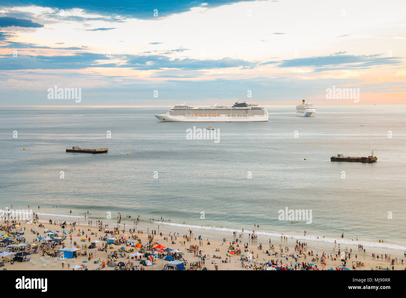 Vue aérienne de la plage bondée avec deux grands navires de croisière à l'horizon au coucher du soleil. Banque D'Images