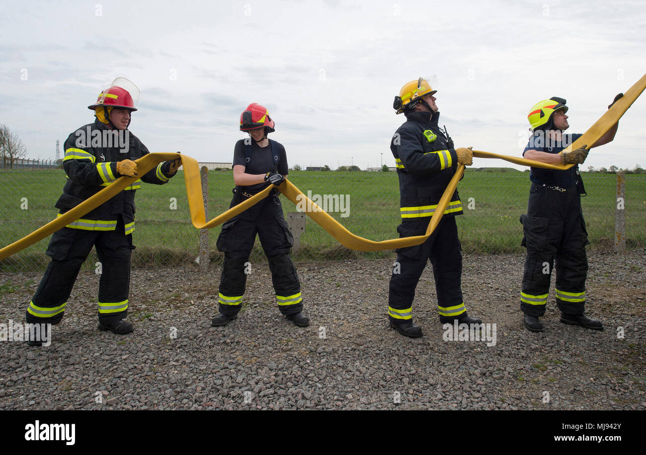 U.S. Air Force Eugene Elking CMSgt (à gauche), 423rd Air Base Group Surintendant, et les pompiers de l'escadron de Génie Civil 423rd charger un tuyau d'incendie à l'arrière d'un camion d'incendie au cours d'un événement de formation incendie à RAF Molesworth, Angleterre le 23 avril 2018. Au cours de l'événement, CMSgt Elking a eu l'occasion de s'entraîner avec les pompiers et d'observer leurs compétences spécialisées. (U.S. Air Force photo de Tech. Le Sgt. Brian Kimball) Banque D'Images