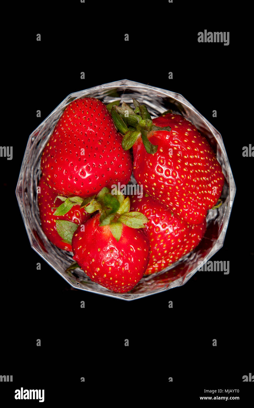 Les fraises dans le verre cristal sur fond noir Banque D'Images