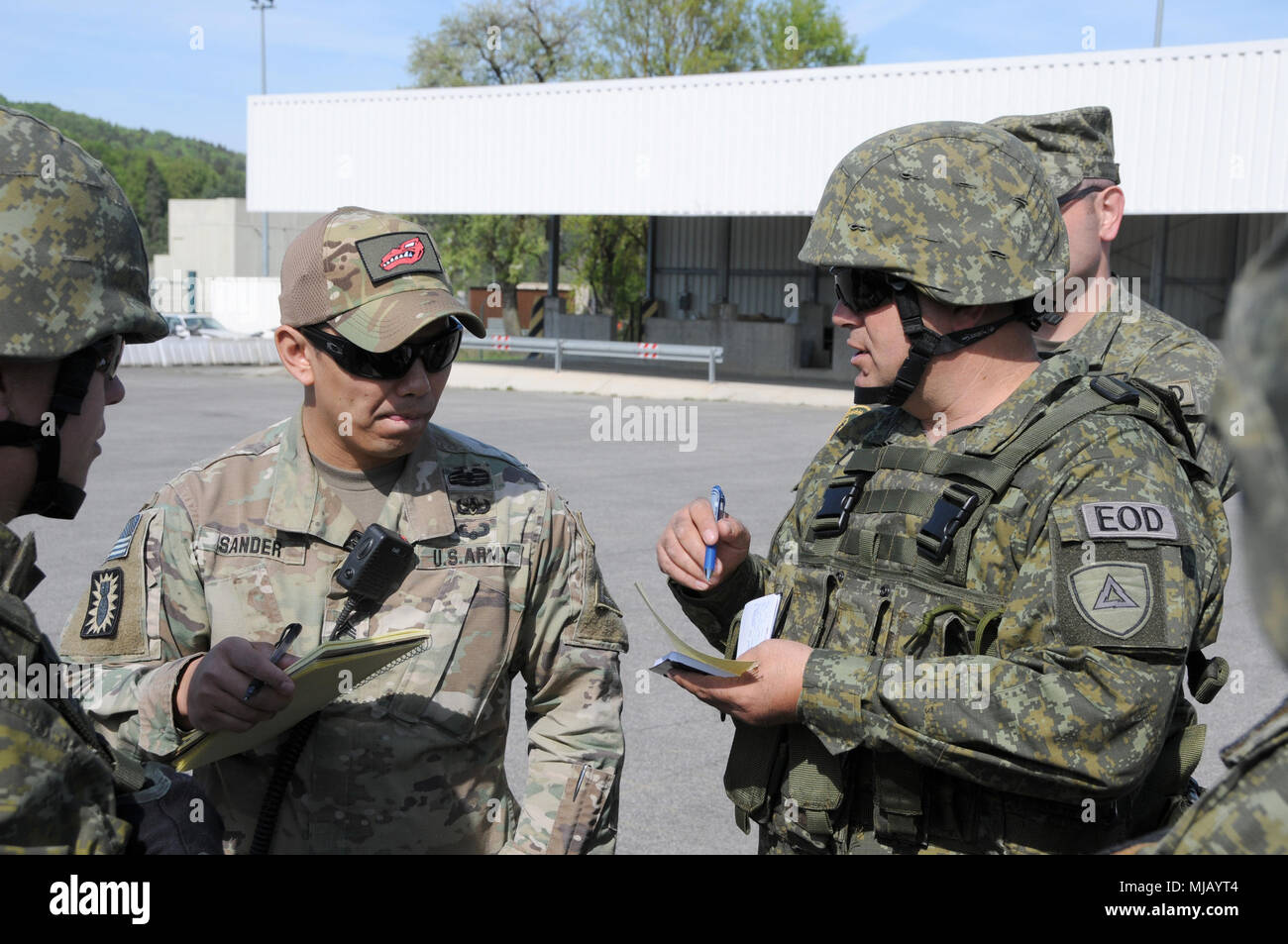 Le personnel de l'Armée du Kosovo Le Sgt. L'Islam Kadriu, chef de l'équipe de neutralisation des explosifs et munitions, compagnie, régiment de protection civile du Kosovo donne une brève mission de l'armée américaine pour le Sgt. 1re classe Marie Sander, un observateur des explosifs et munitions coach/entraîneur avec l'équipe de rapaces, affecté à l'état de préparation interarmées multinationale Centre, avant d'exécuter la formation sur l'engin explosif dans les Hohenfels Domaine de formation, Hohenfels, Allemagne, pendant les résoudre X le 27 avril 2018. Résoudre X combiné comprend environ 3 700 participants de 13 nations à la 7e formation de l'Armée de terre Grafenw la commande Banque D'Images