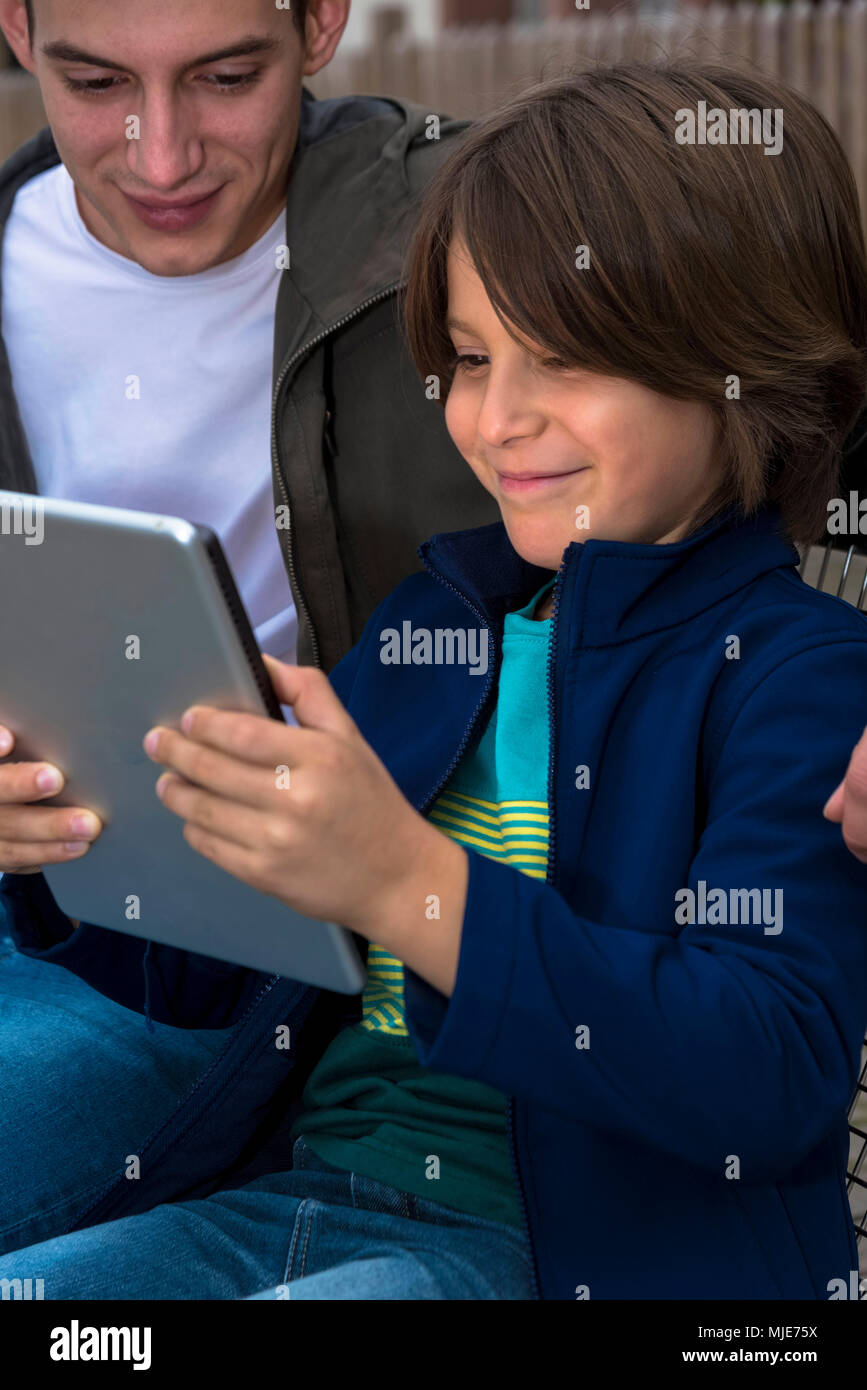 Jeune homme et enfant avec tablette, s'asseoir, sourire Banque D'Images