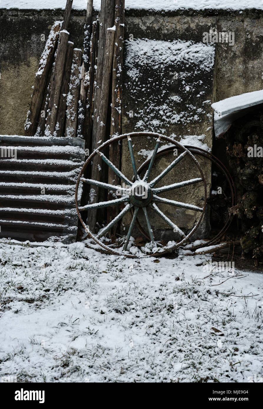 Ancienne ferme, la roue, de la tôle ondulée et de bois sur un mur, la neige Banque D'Images