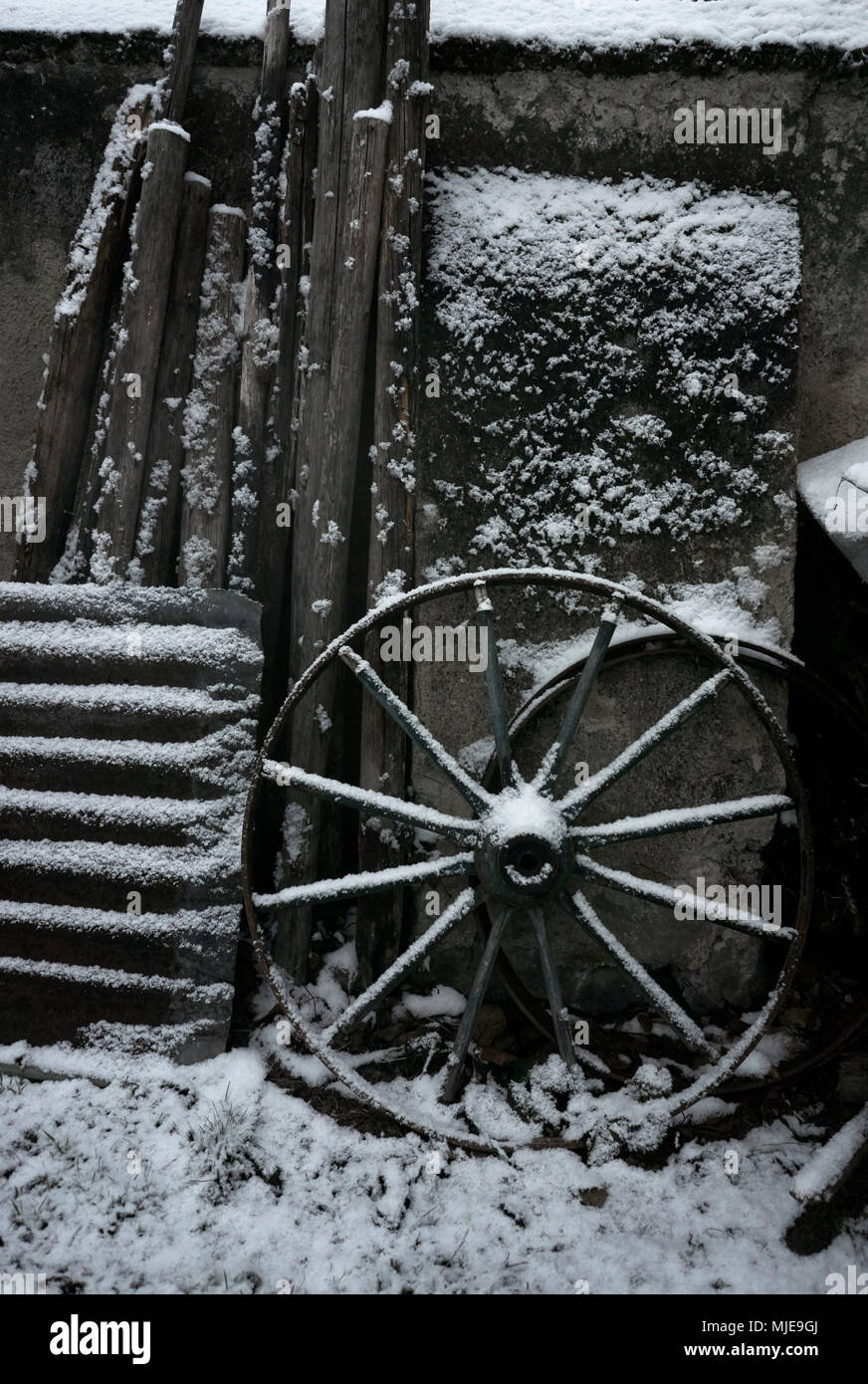 La roue, de la tôle ondulée et de bois sur un mur dans une ferme avec de la neige Banque D'Images