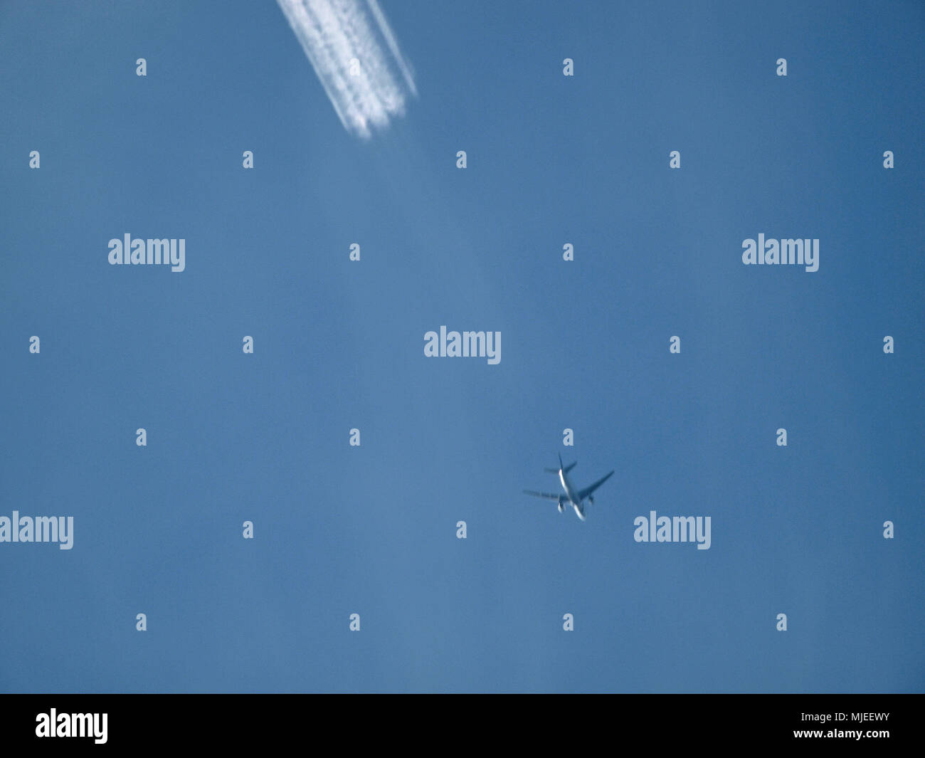 Avion et les chemtrails dans le ciel bleu Banque D'Images