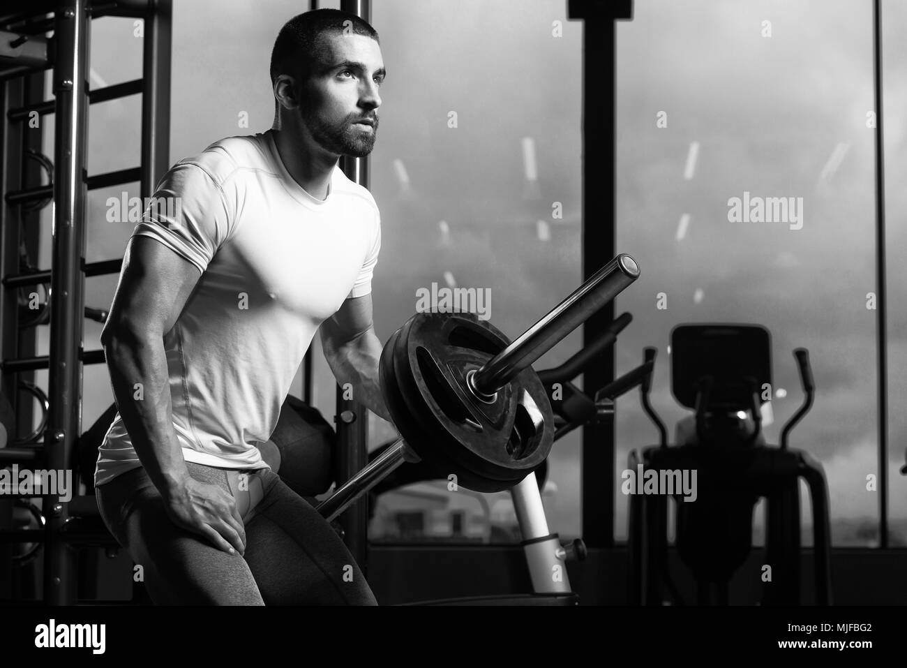 L'homme musclé faisant poids lourd pour l'exercice d'haltères avec retour en salle de sport Banque D'Images