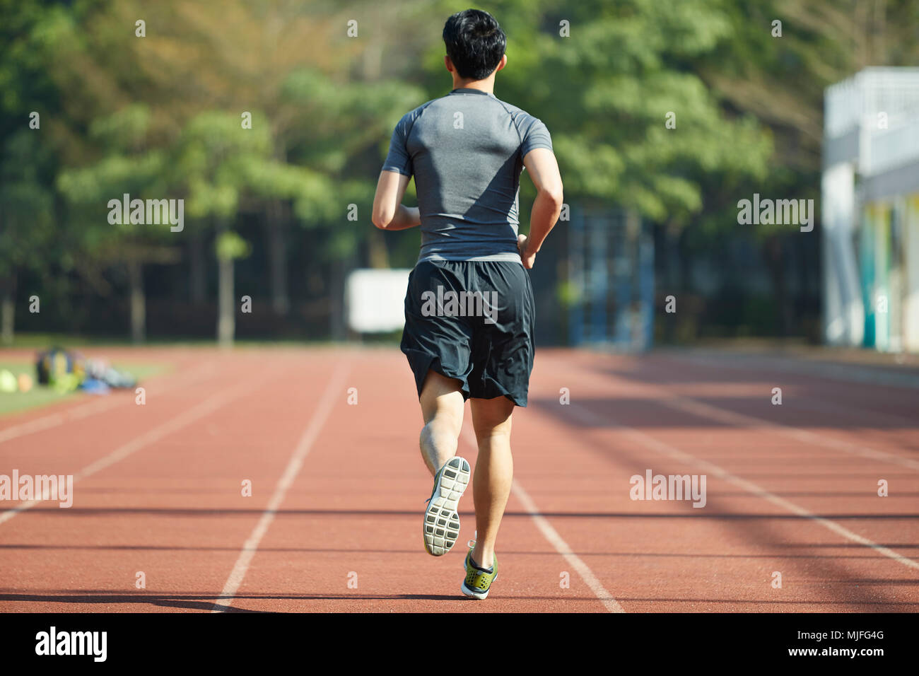 Jeune athlète masculin homme asiatique d'exécution de l'exercice de formation sur la voie, vue arrière. Banque D'Images