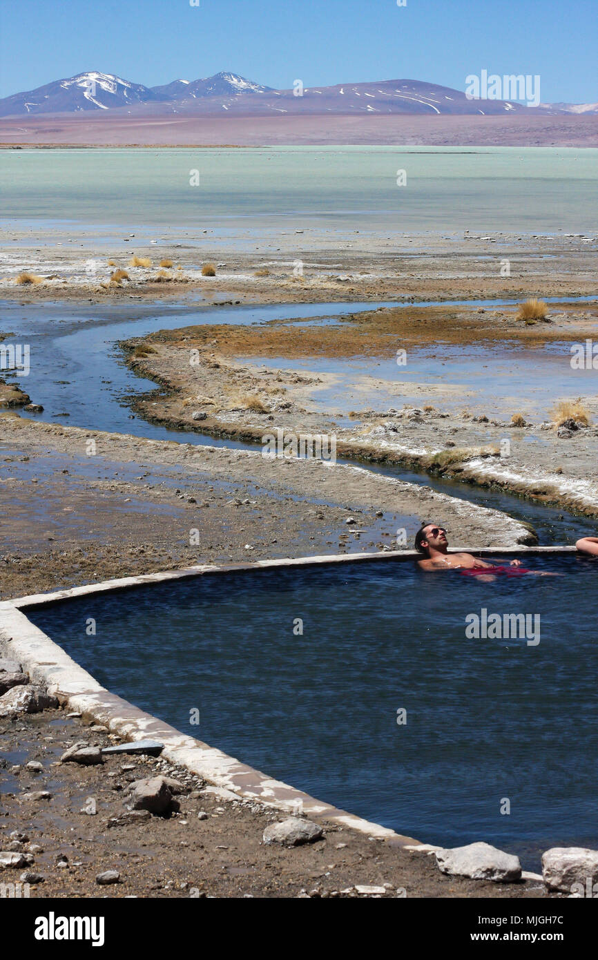 TUPIZA, BOLIVIE - 23 septembre 2011 : Un homme se détend dans les sources chaudes de Salar de Uyuni tout en appréciant le magnifique paysage du désert Banque D'Images