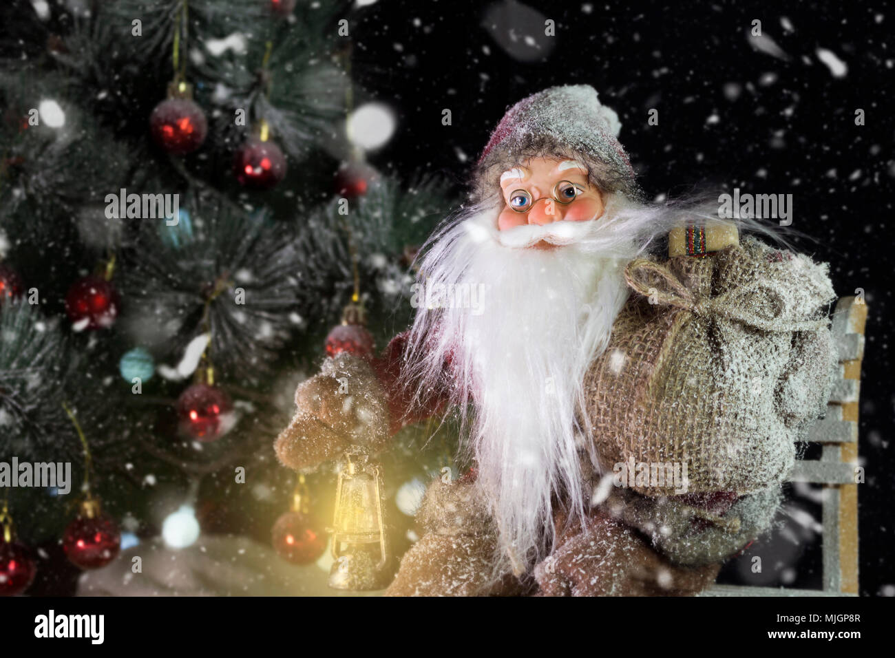 Le Père Noël en plein air à côté d'arbre de Noël dans la neige transportant des cadeaux aux enfants. Joyeux Noël & Nouvel An concept Banque D'Images