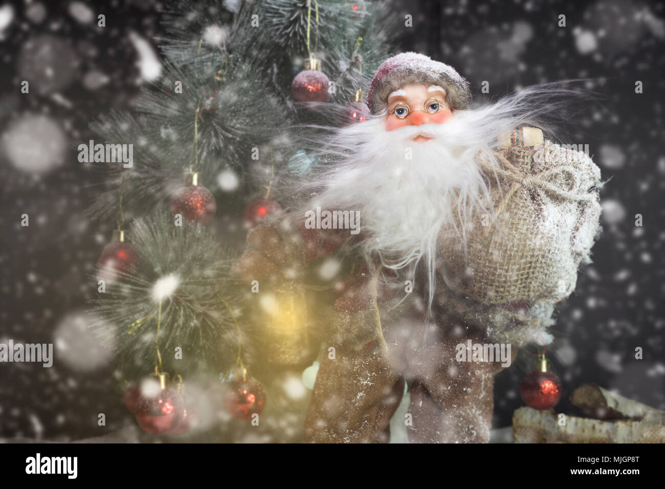 Le Père Noël en plein air à côté d'arbre de Noël dans la neige transportant des cadeaux aux enfants. Joyeux Noël & Nouvel An concept Banque D'Images