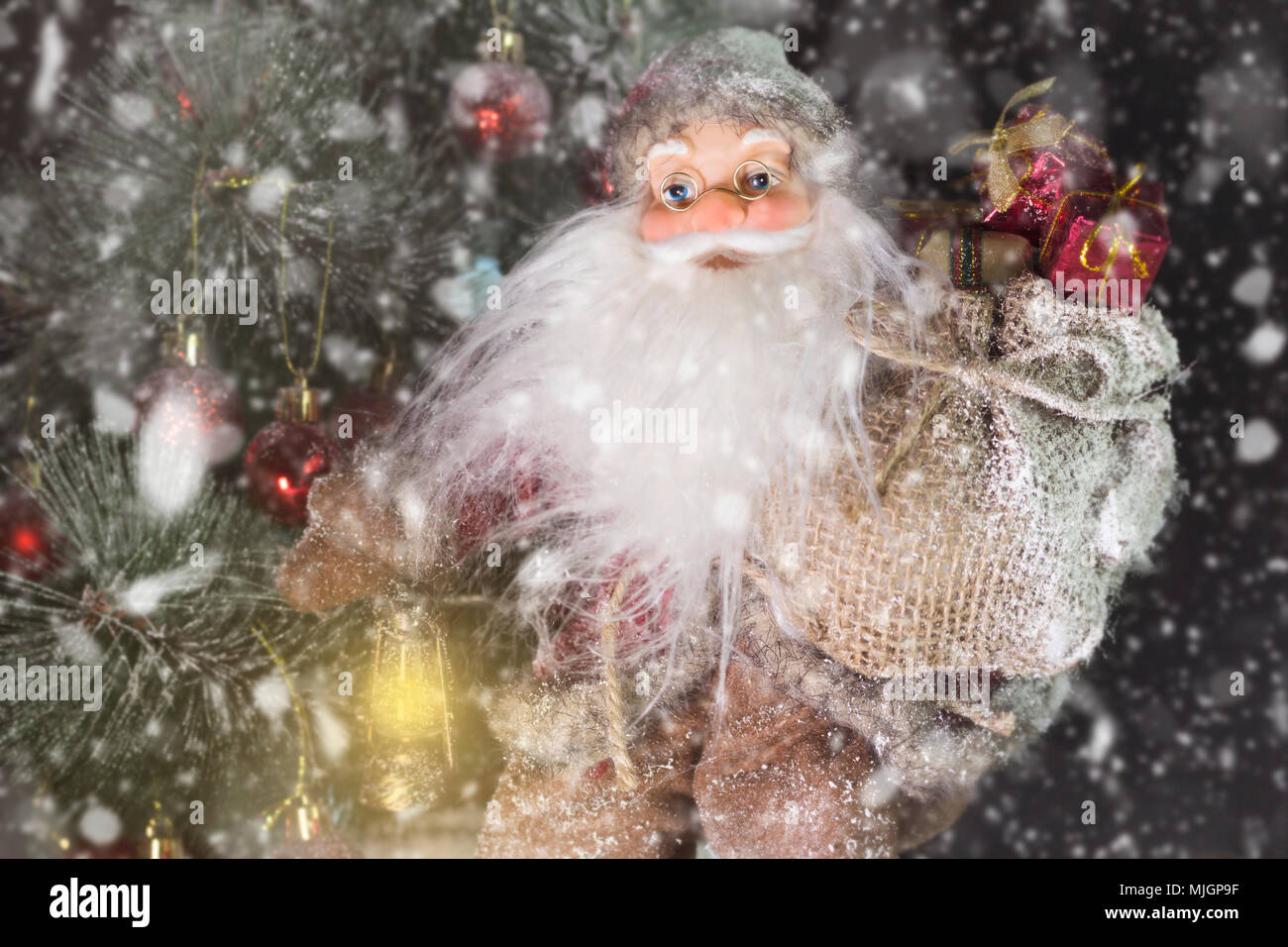 Le Père Noël en plein air à côté d'arbre de Noël dans la neige transportant des cadeaux aux enfants. Joyeux Noël & Nouvel An concept Banque D'Images