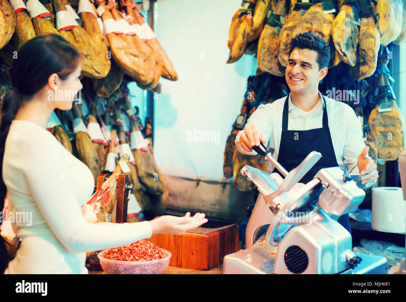 Jeune brunette choosing jamon serrano et iberico et souriant Banque D'Images