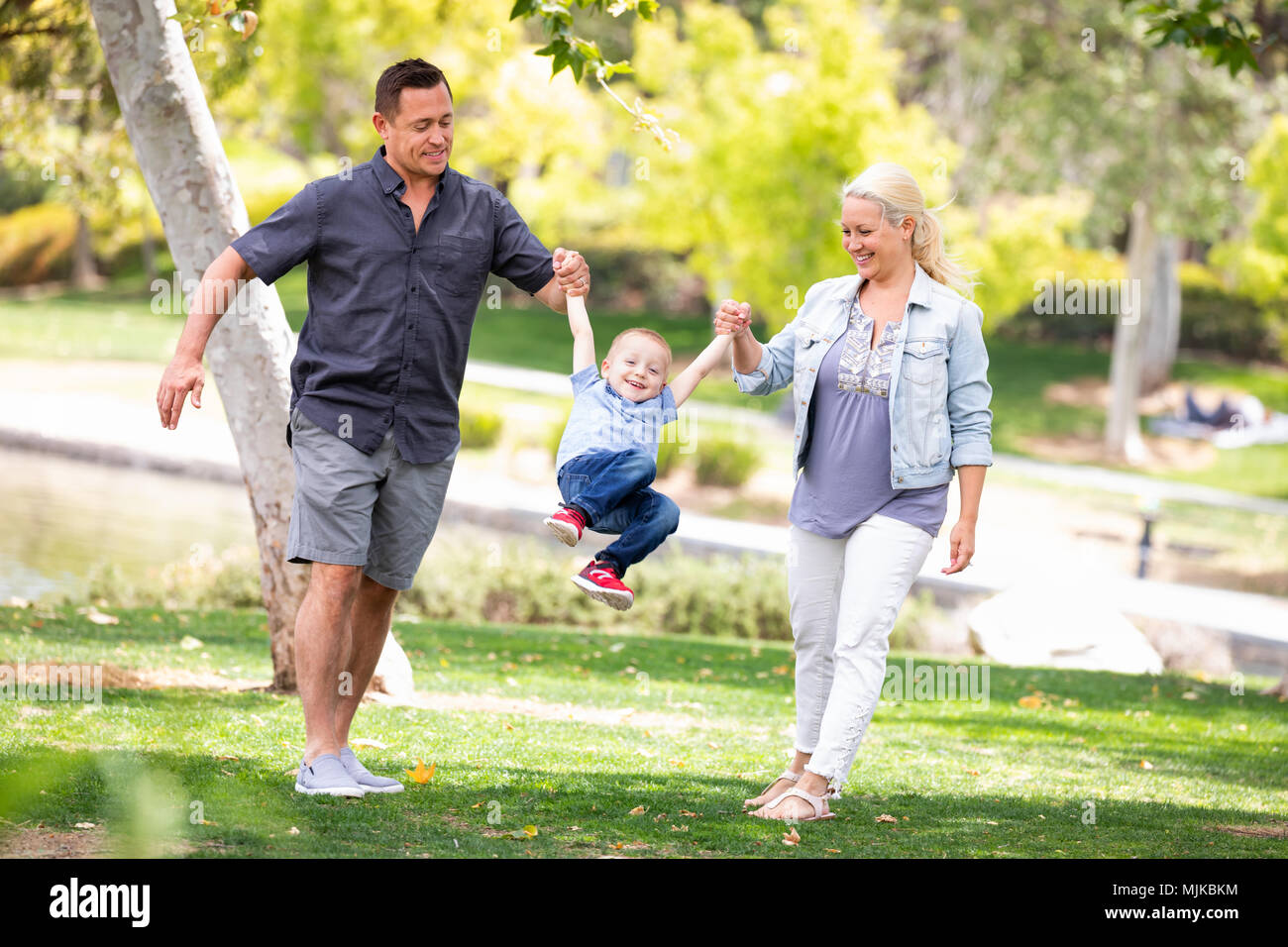 Jeune mère et père Swingging leur fils au parc. Banque D'Images