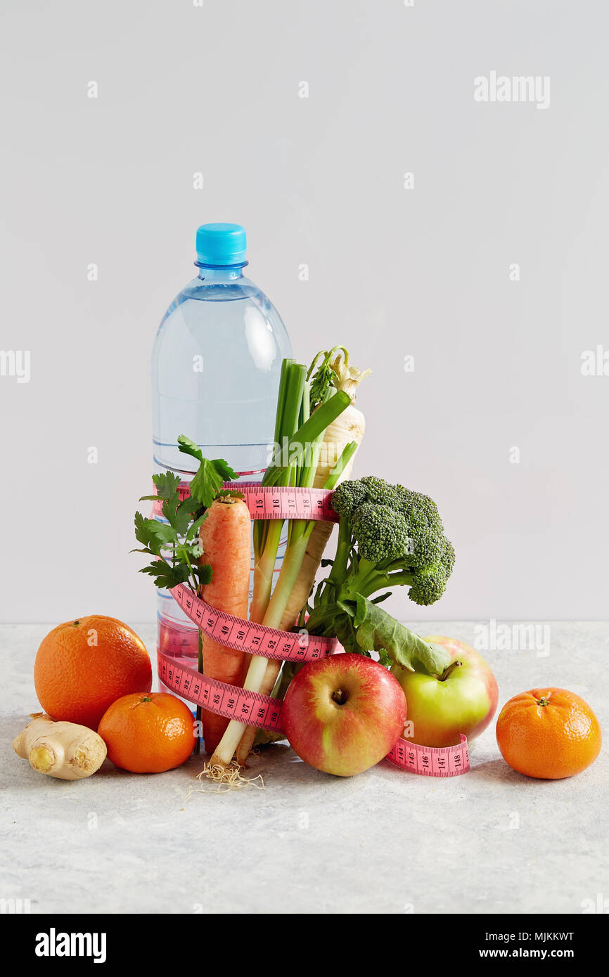 Bouteille de l'eau avec un ruban rose, légumes et fruits. Concept de la santé, de l'alimentation et la nutrition. Banque D'Images
