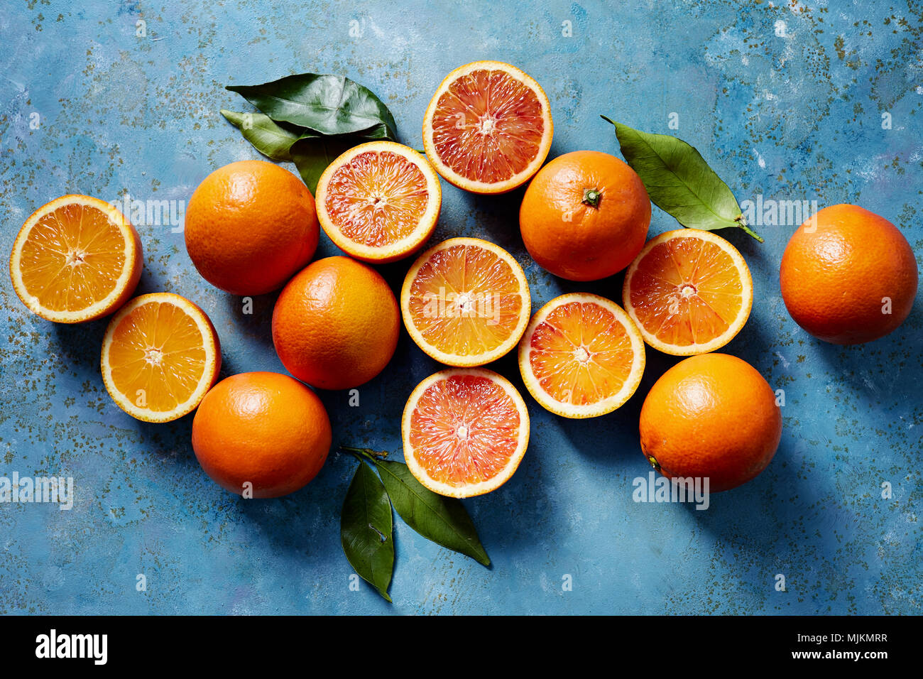 Orange sanguine entières ou coupées en tranches sur une surface bleue (vu du dessus). Banque D'Images