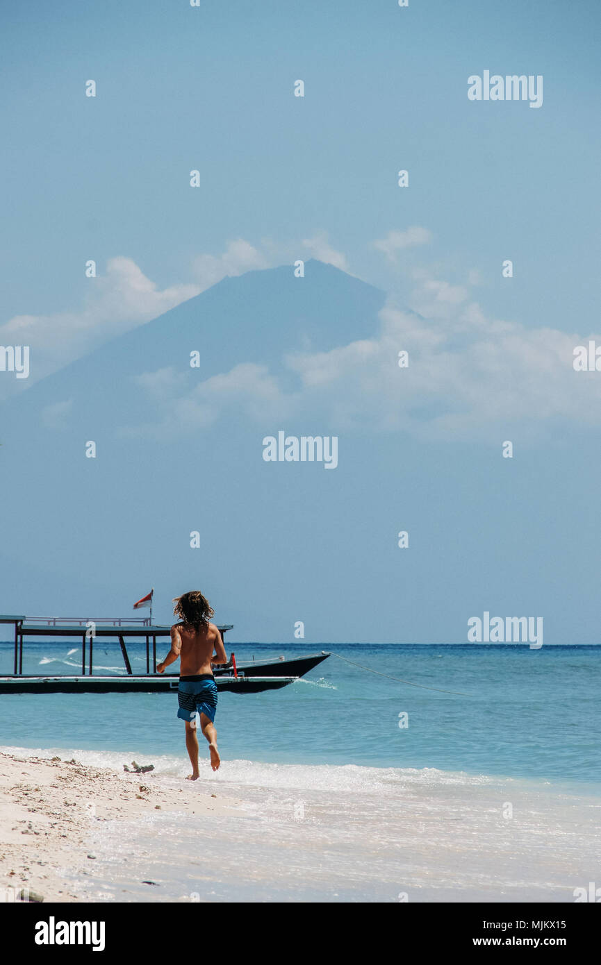Fonctionne homme plage de sable blanc sur fond de montagne avec des nuages en haut Banque D'Images